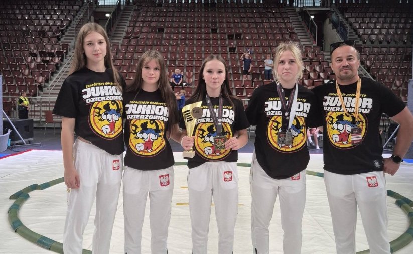 Cztery zawodniczki i trener na białej macie do walk sumo