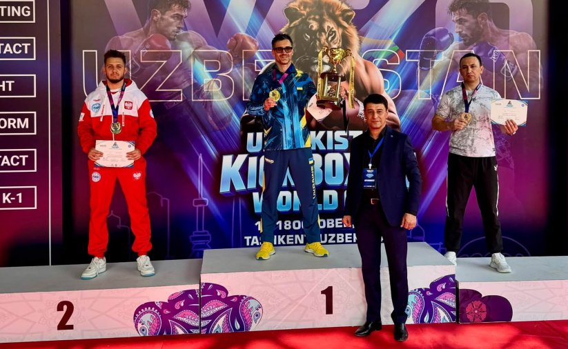 Maksymilian Palej w biało-czerwonym stroju reprezentacji Polski stoi na drugim miejscu podium. Za nim napis Uzbekistan