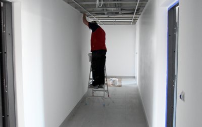 Pracownik montujący instalaję elektryczną na korytarzu
