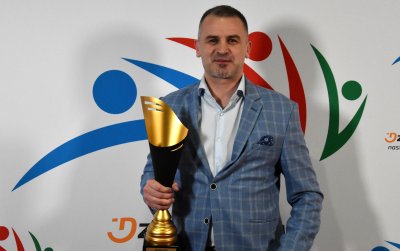 Mężczyzna w marynarce ze złotym pucharem w dłoni