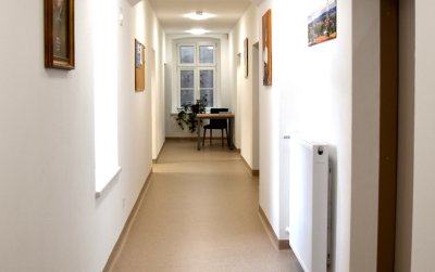 Korytarz, białe ściany po bokach drzwi i okna