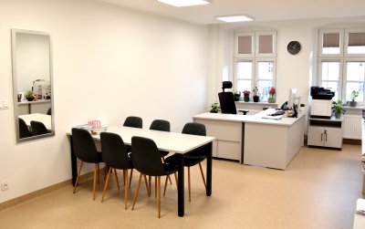 Pomieszczenie z dużym stołem i dwoma biurkami