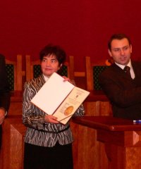 Dyrektorka biblioteki trzymająca w ręku dyplom, obok burmistrz i przewodniczący rady