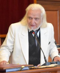 Marek Cieśla w białej marynarce przy mówinicy