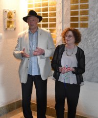 Kobieta i mężczyzna - przedstawiciele synagogi stojący przy kamiennej tablicy pamiątkowej
