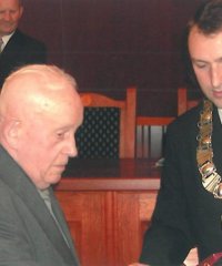 Władysław Janiec odbierający medal z rąk przewodniczącego rady