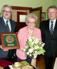 Zofia Cupak z kwiatami, po bokach burmitrz i przewodniczący rady