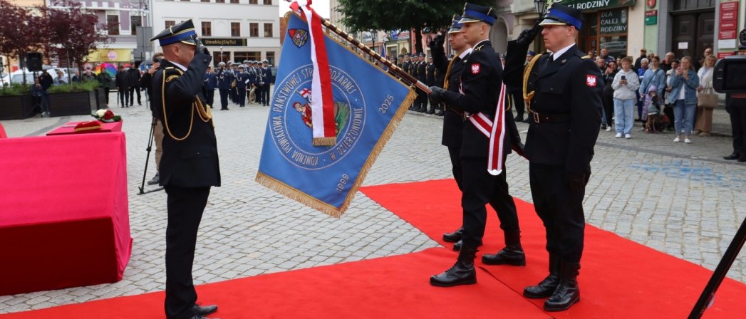 oficer straży pożarnej salutujący przy poczcie sztandarowym