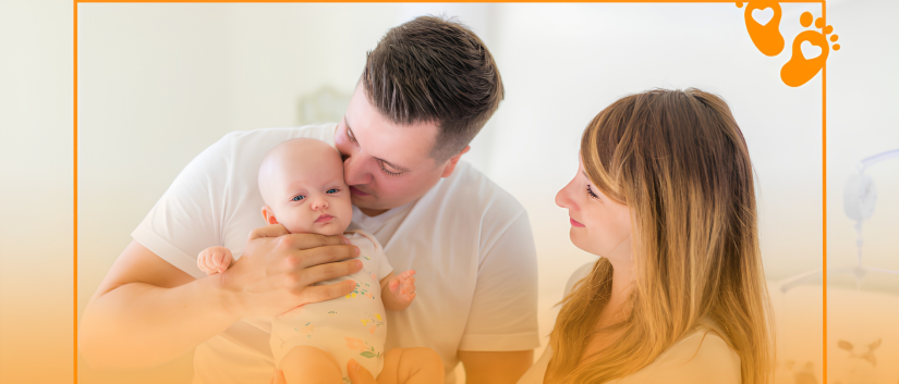 Ojciec trzymający i całujący niemowlaka, obok mama